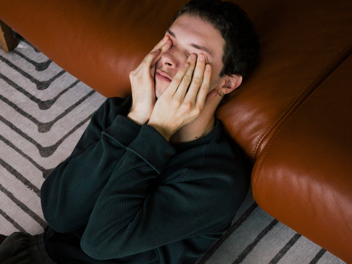 Junger Mann hält sich die Hände vor das Gesicht