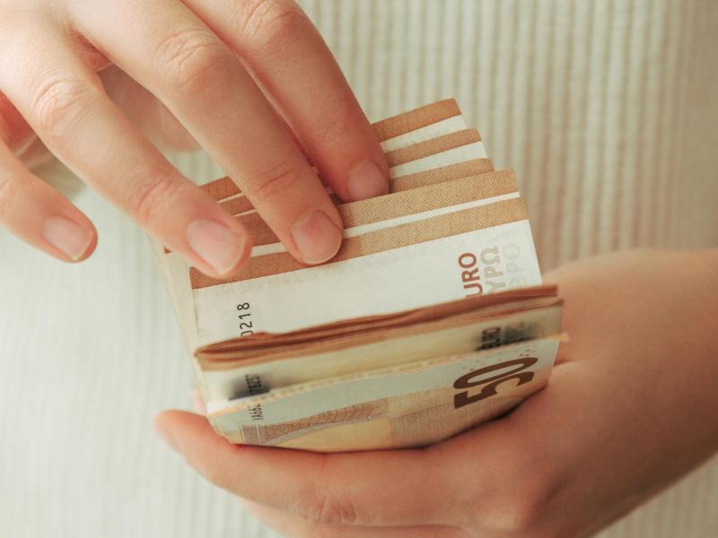 Frau mit hellem Pulli zählt 50-Euro-Scheine.