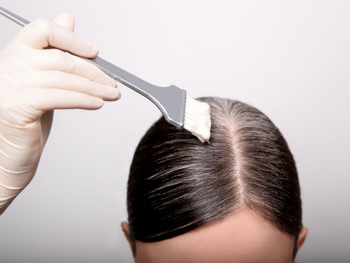 Frau, die gerade ihre graun Ans&auml;tze f&auml;rbt.