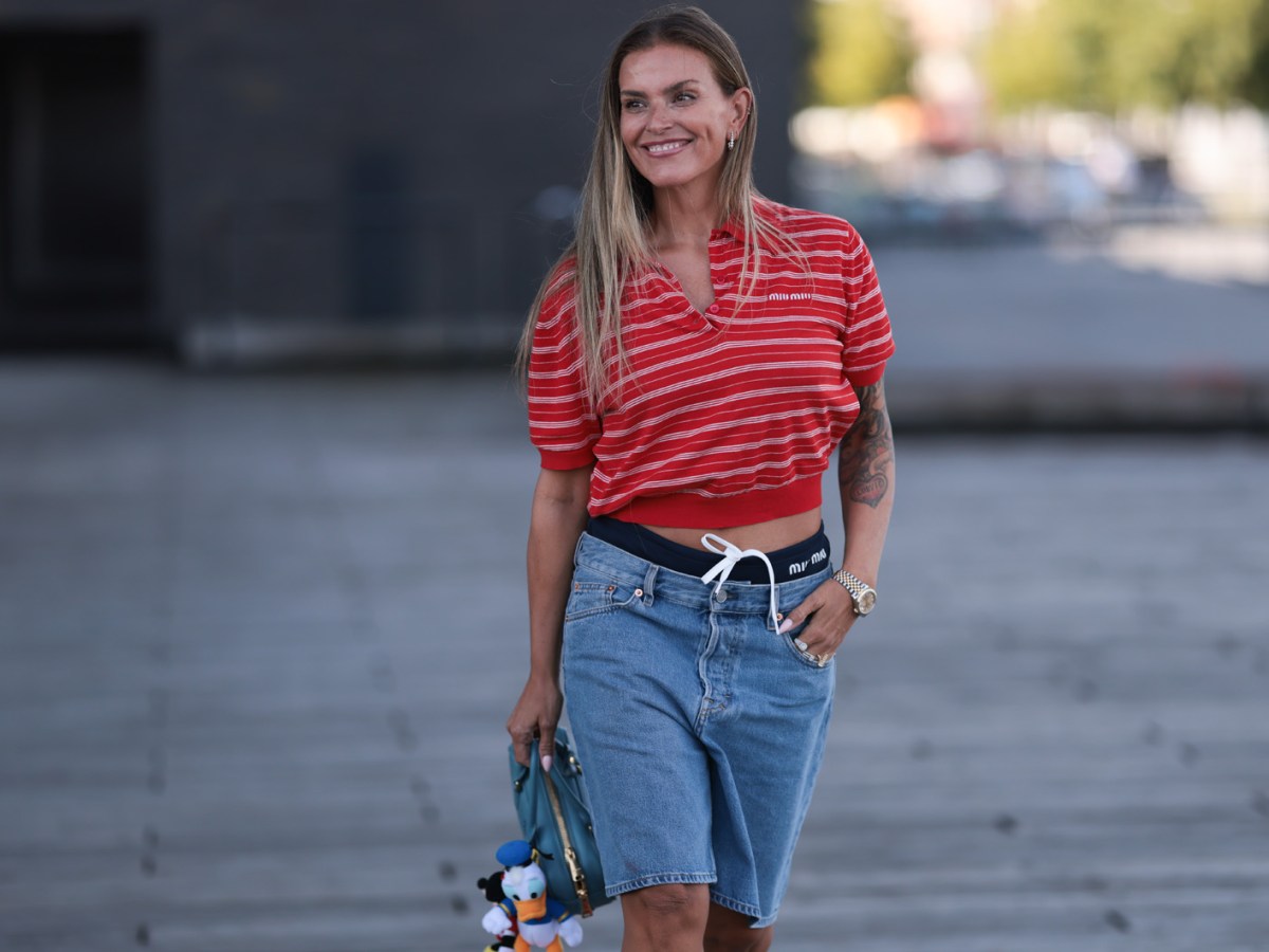 Influencerin Janka Polliani in einer kurzen Denim-Shorts und rotem Polohemd.