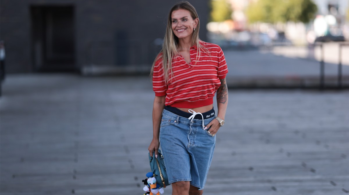 Influencerin Janka Polliani in einer kurzen Denim-Shorts und rotem Polohemd.