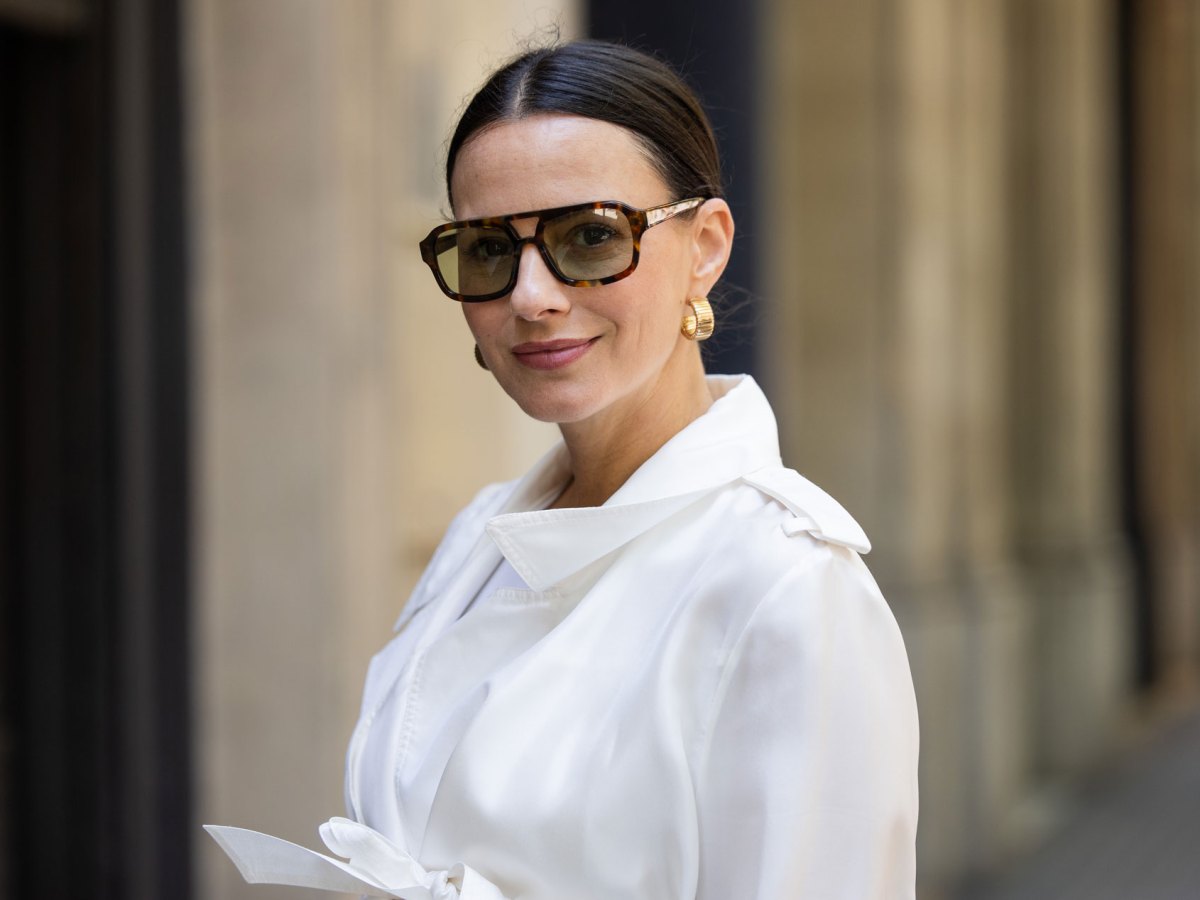 Frau mit wei&szlig;er Bluse und brauner Sonnenbrille.