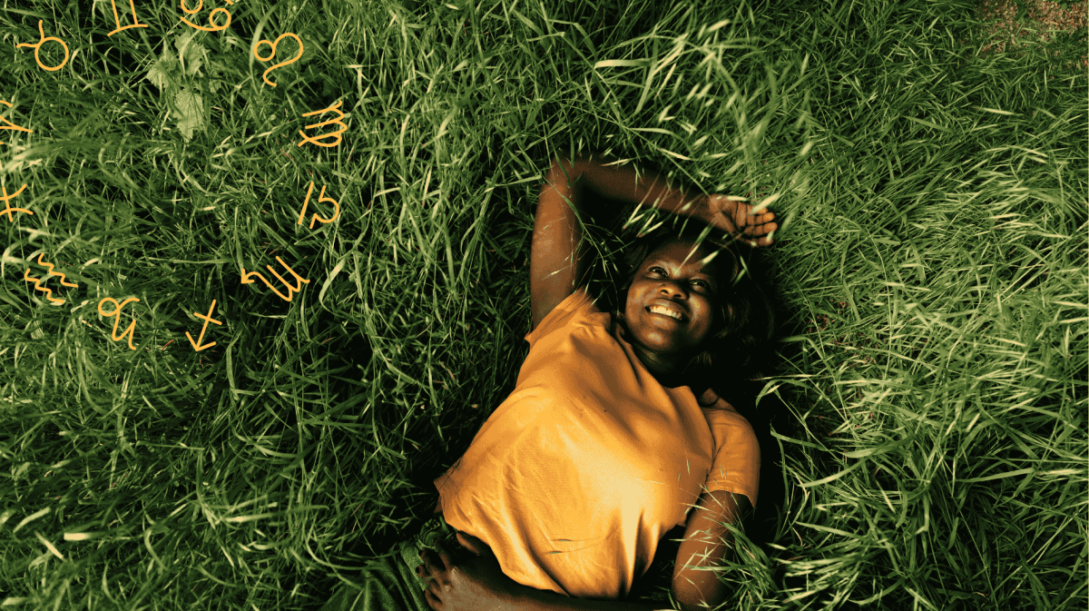 Frau mit gelbem Shirt liegt lächelnd im Rasen