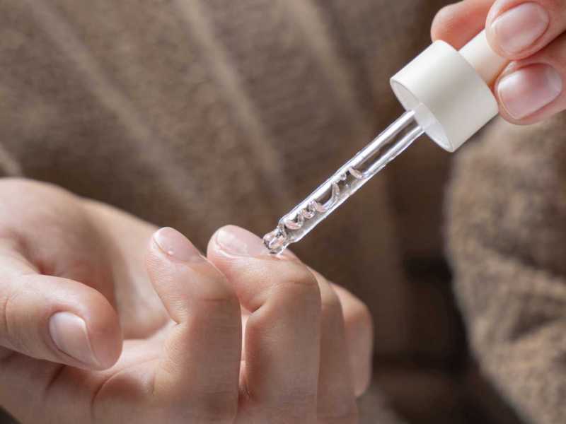 Mit einer Pipette wird Öl auf die Nägel aufgetragen