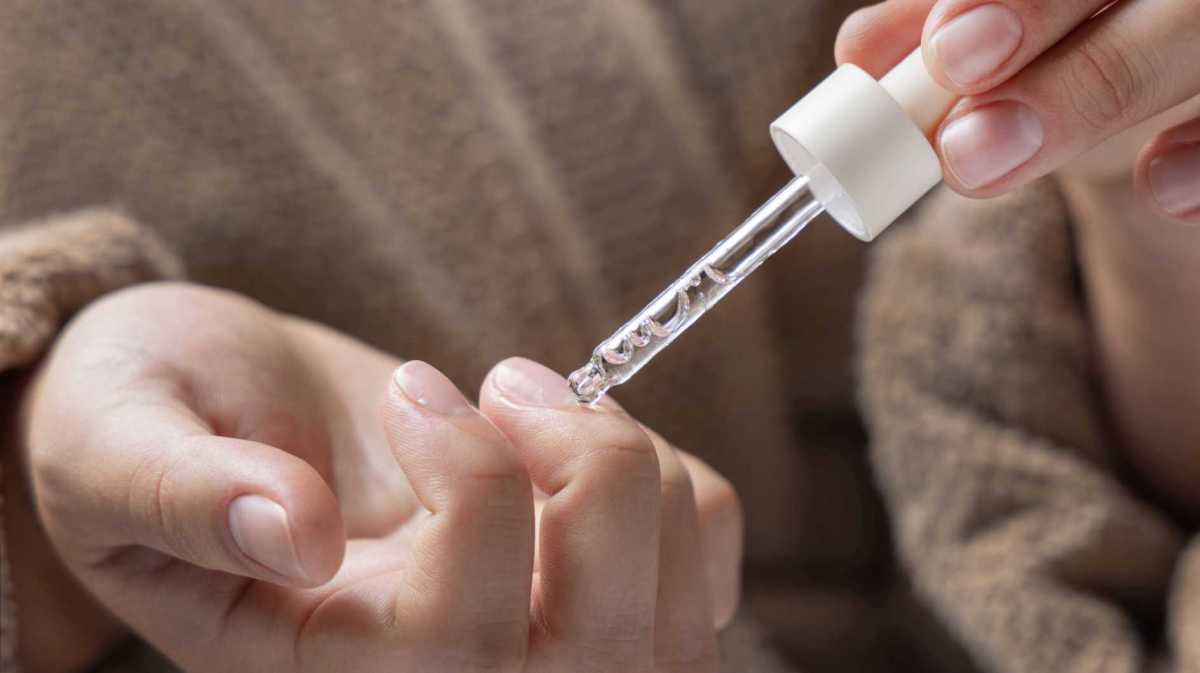 Mit einer Pipette wird Öl auf die Nägel aufgetragen
