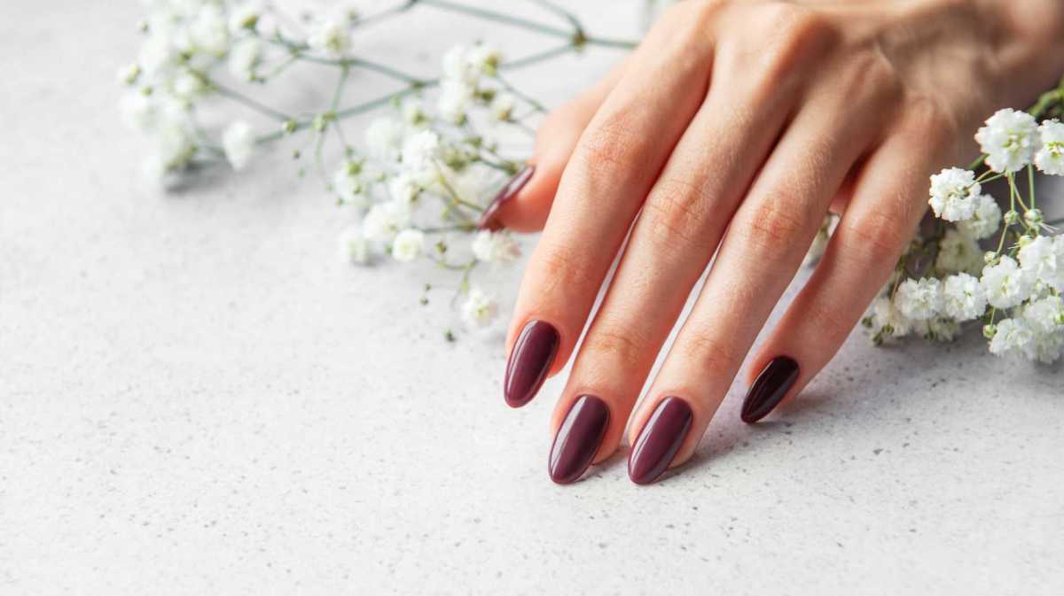 Rot lackierte Fingernägel vor weißen Blumen