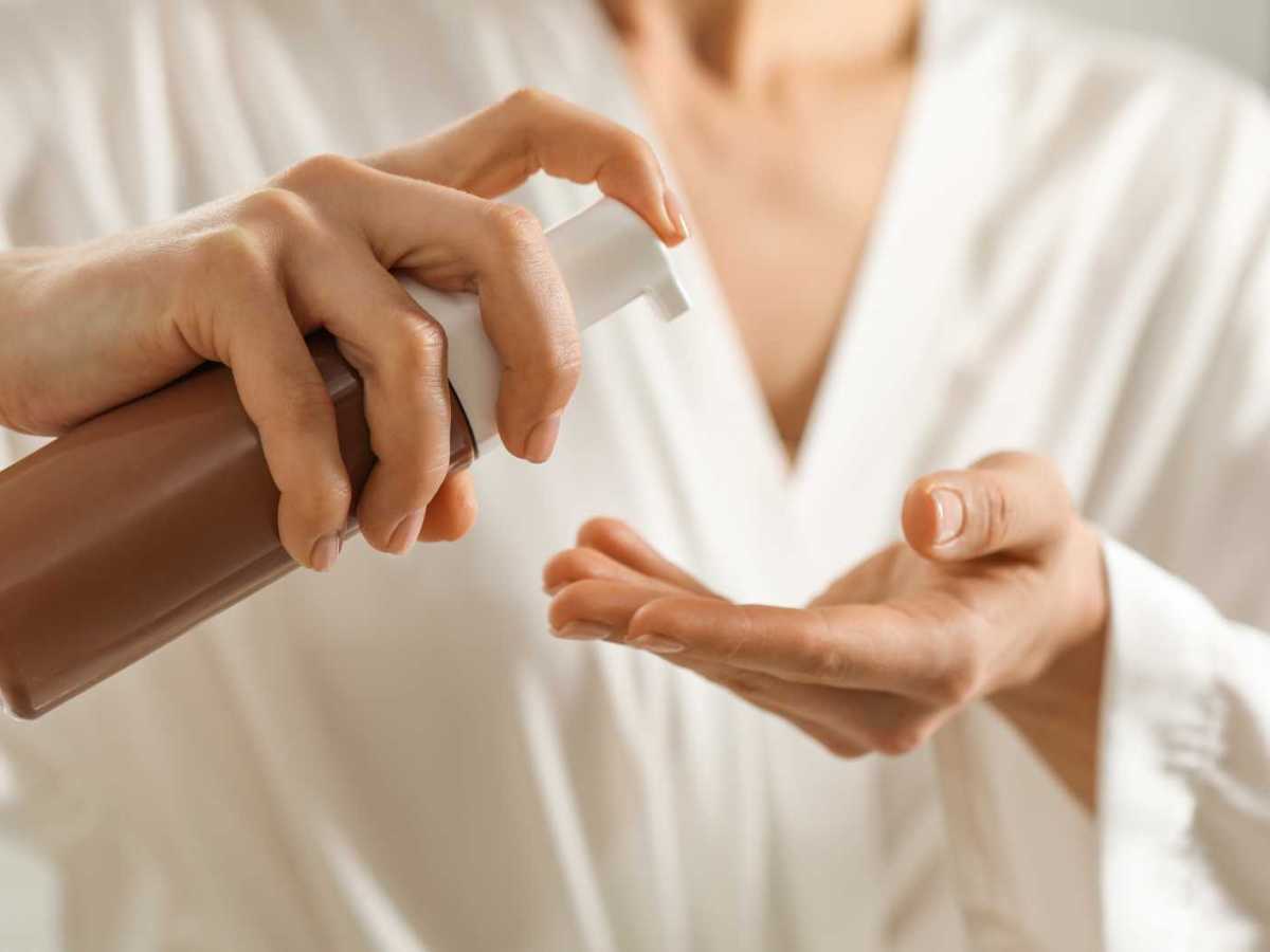 Frau gibt Selbstbr&auml;uner in die Handfl&auml;chen