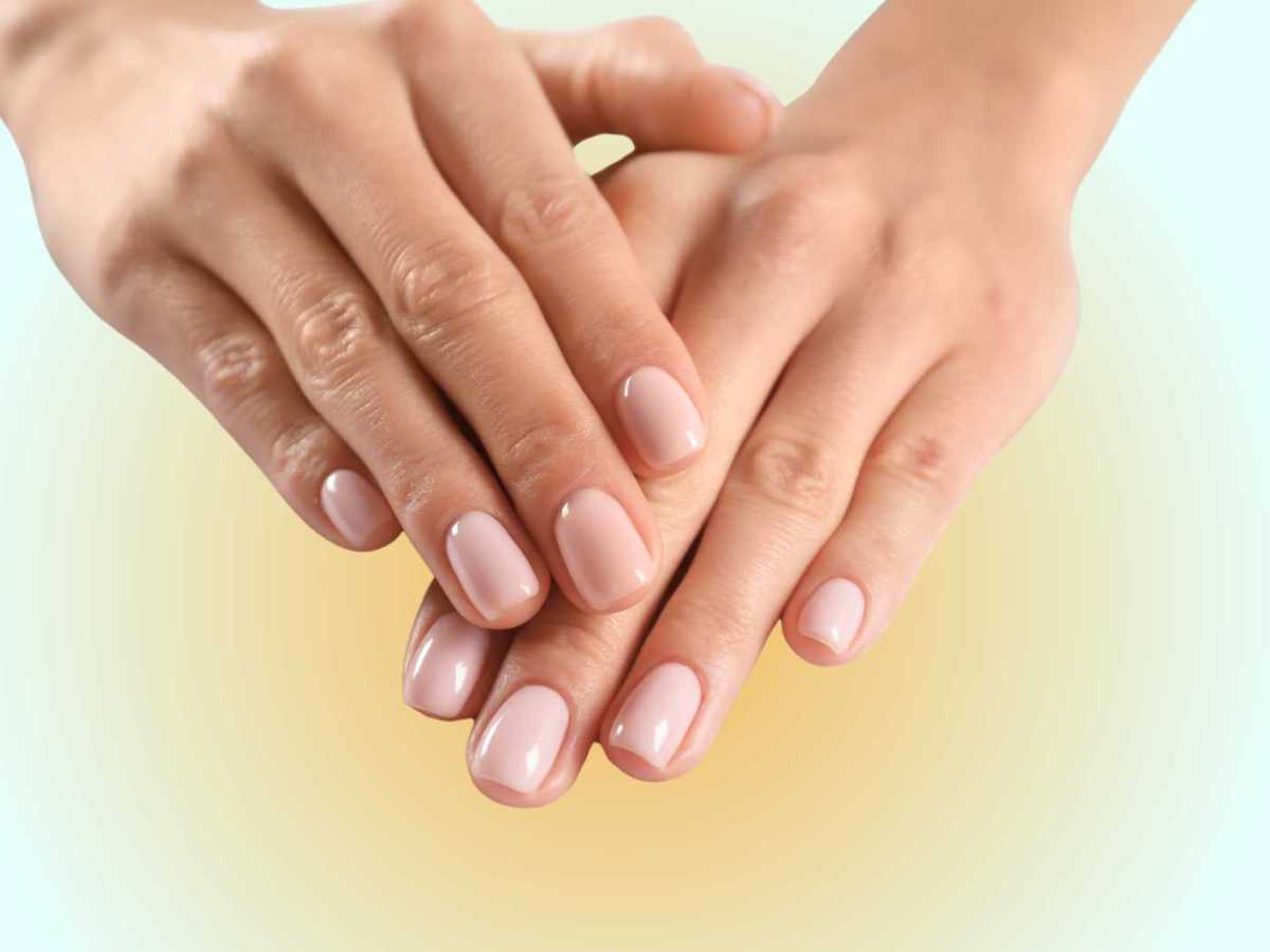 Zwei H&auml;nde mit rosa lackierten Fingern&auml;geln werden vor einen blau-orangenen Hintergrund gehalten