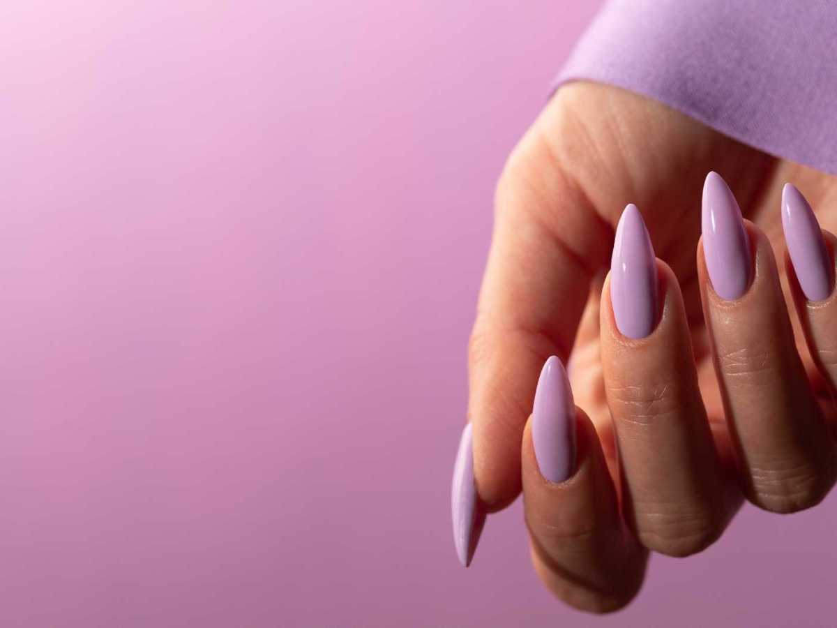 Hand mit langen, lilafarben lackierten Nägeln
