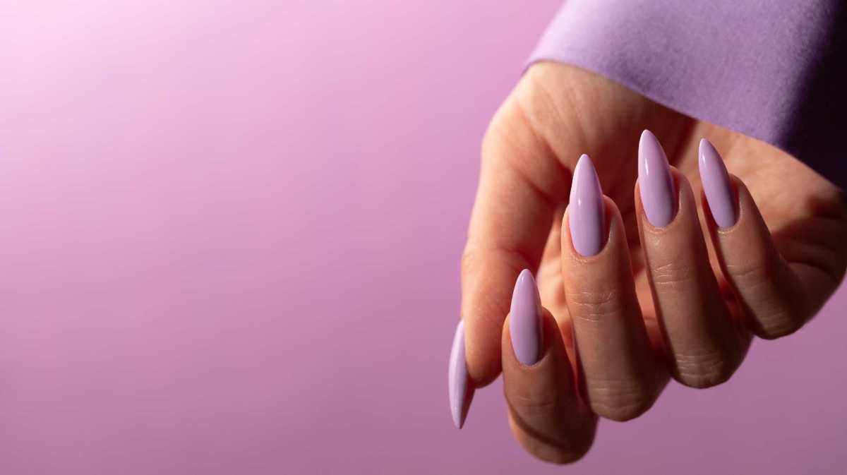 Hand mit langen, lilafarben lackierten Nägeln