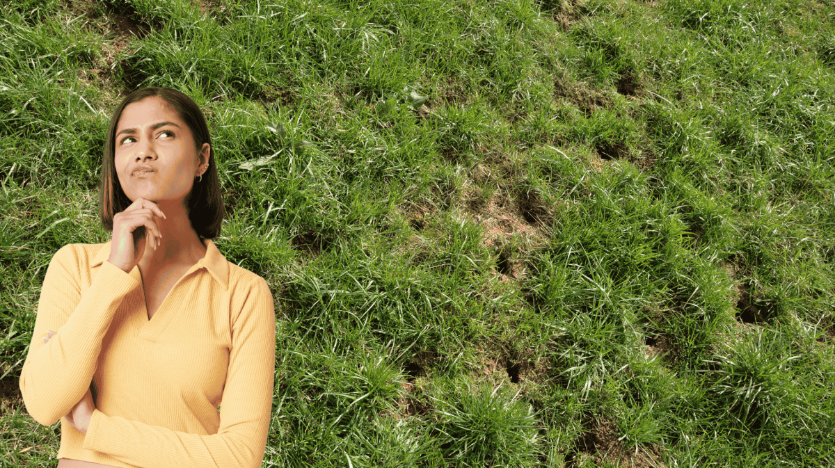 Frau schaut nachdenklich im Hintergrund Rasen mit Löchern