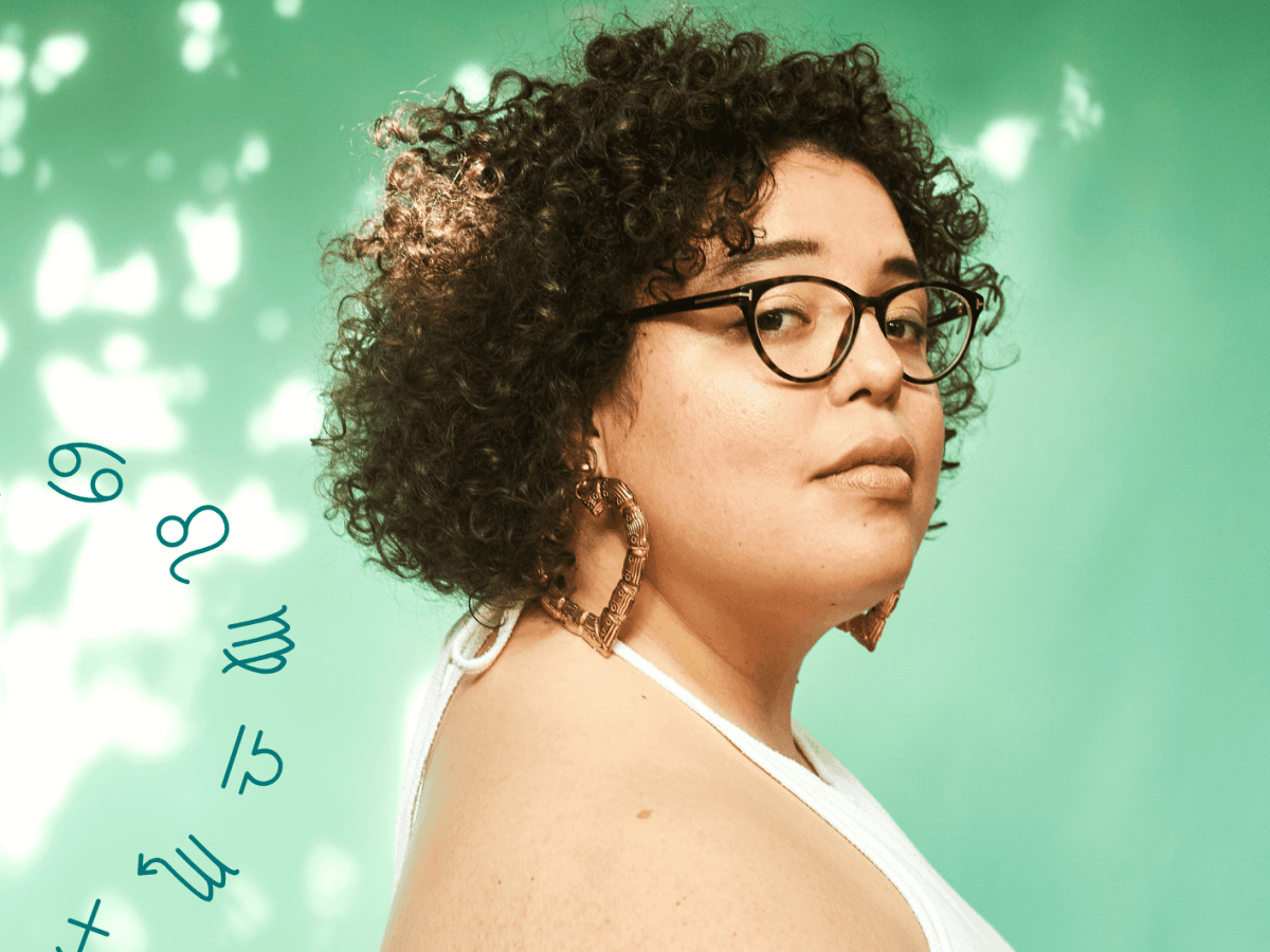 Frau mit Brille steht vor einem hellgr&uuml;nen Hintergrund und guckt skeptisch in die Kamera.