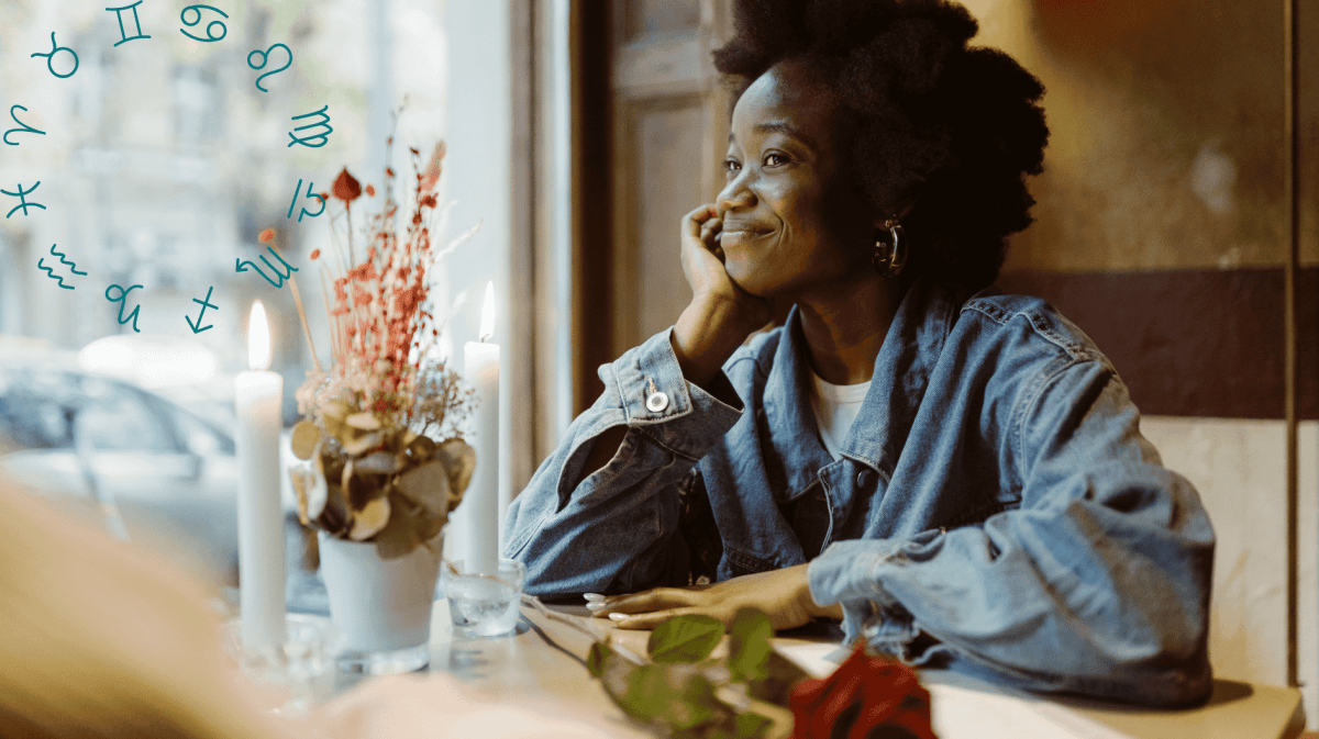 Frau an einem Tisch lächelt bei Kerzenschein, eine Rose liegt auf dem Tisch