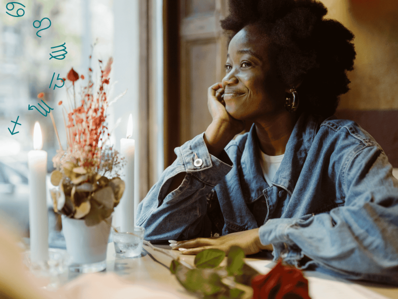 Frau an einem Tisch lächelt bei Kerzenschein, eine Rose liegt auf dem Tisch