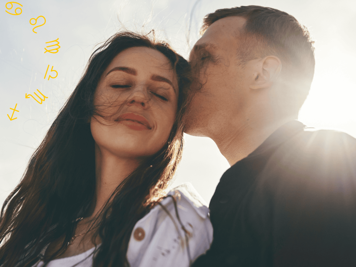 Frau und Mann bei Sonnenschein. Mann k&uuml;sst den Kopf der Frau, sie hat Augen geschlossen.