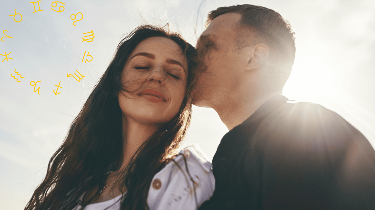 Frau und Mann bei Sonnenschein. Mann küsst den Kopf der Frau, sie hat Augen geschlossen.