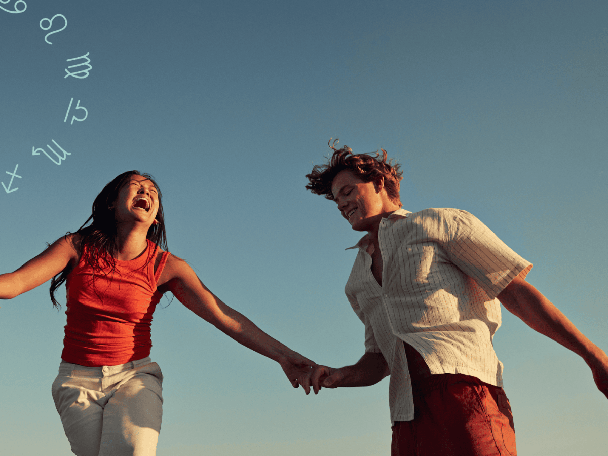 Frau und Mann halten sich an der Hand und lachen zusammen vor blauem Himmel