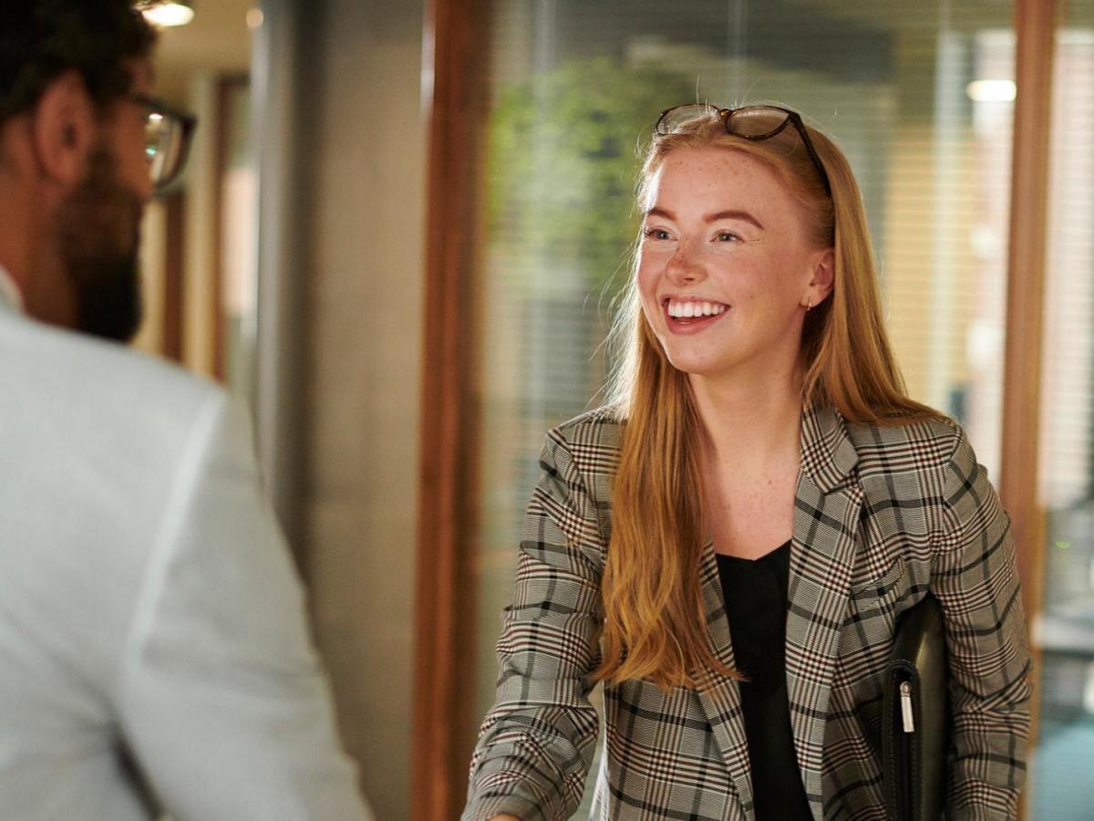 Frau sch&uuml;ttelt einem Mann die Hand.