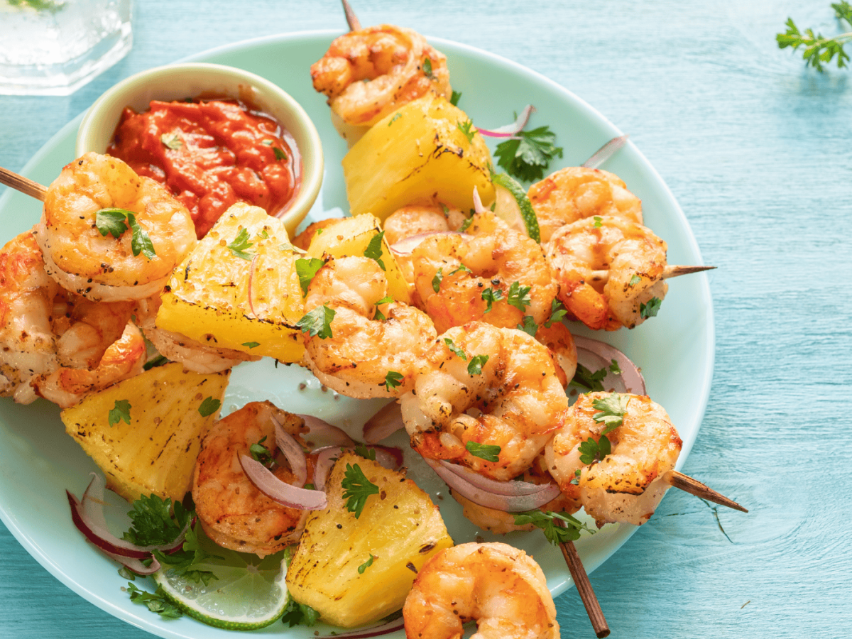 Ananas-Garnelen-Spieße auf einem blauen Teller.