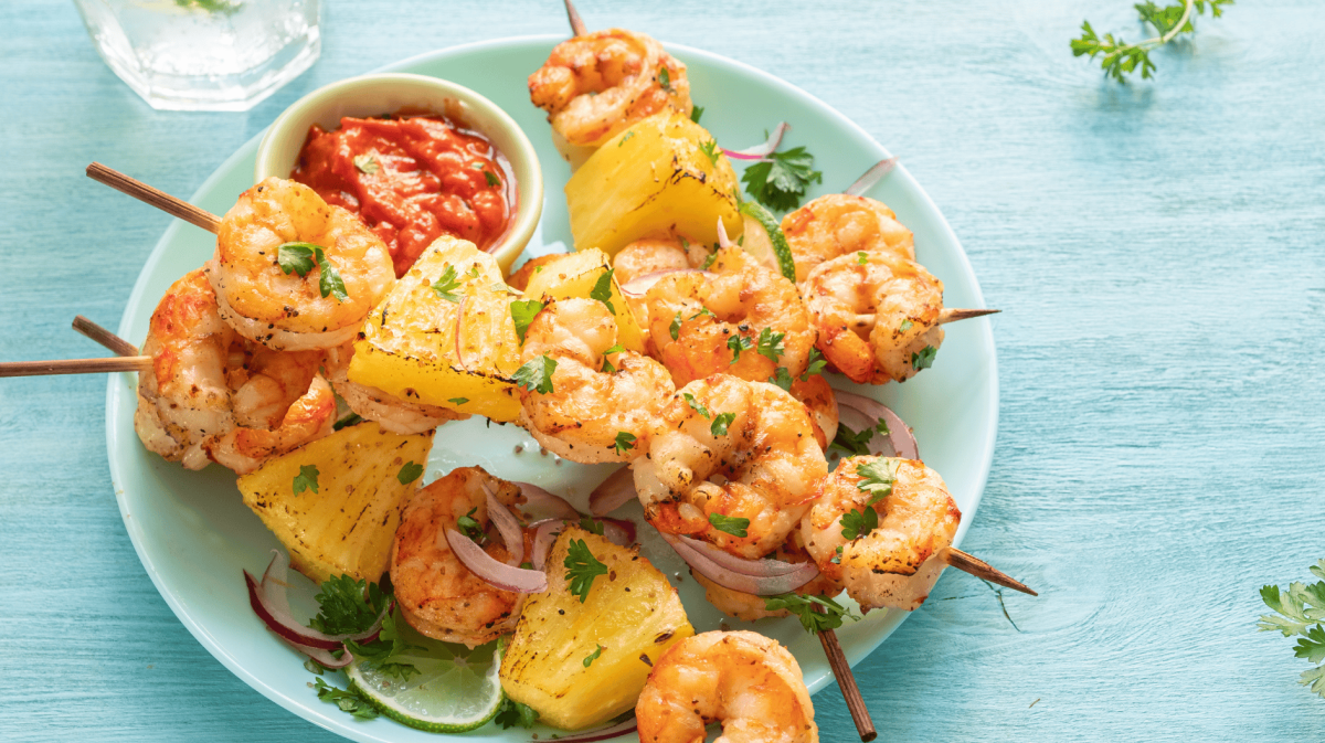 Ananas-Garnelen-Spieße auf einem blauen Teller.