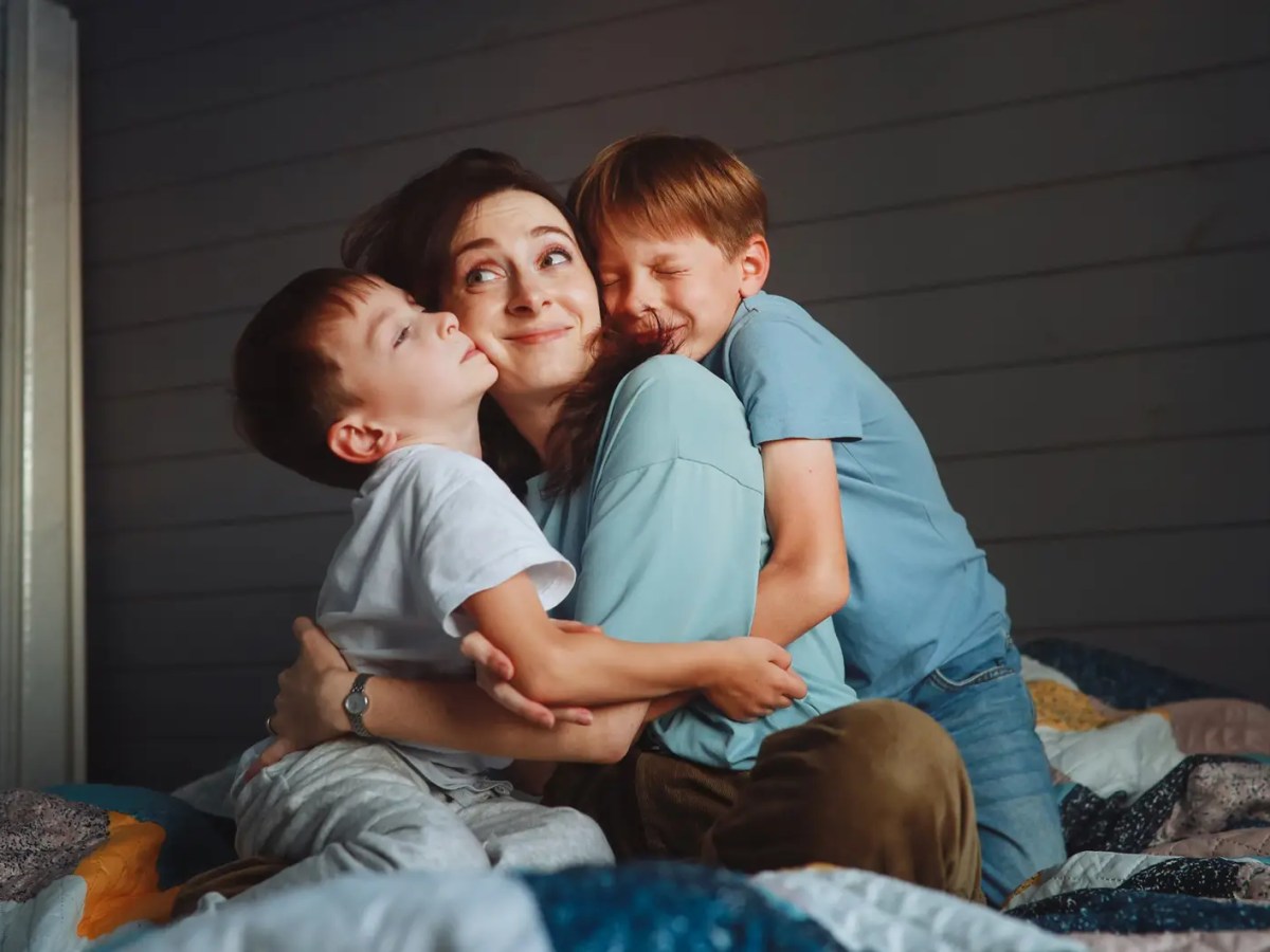 Mutter im Bett, wird von ihren beiden S&ouml;hnen am Morgen herlzlich geweckt.