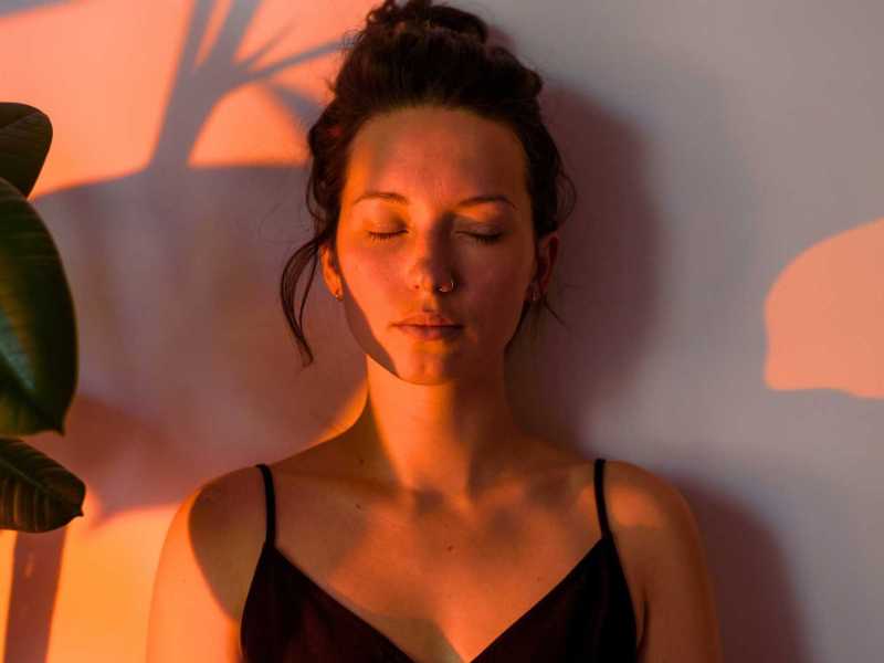 Porträt einer jungen, lockigen, denkenden Frau zu Hause mit Abendlicht.