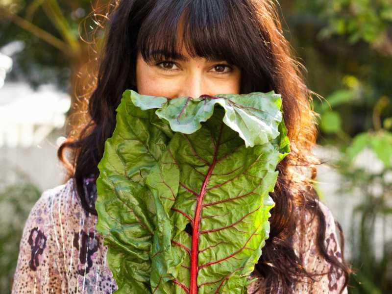 Junge Frau hält Magold-Blatt vor ihrem Gesicht