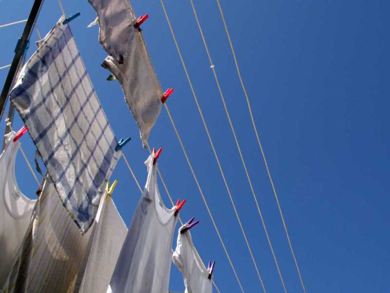 Weiße Kleidung hängt draußen in der Sonne auf einer Wäscheleine