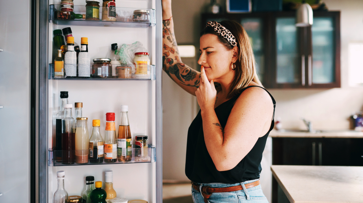 Frau steht unschlüssig vr Kühlschrank