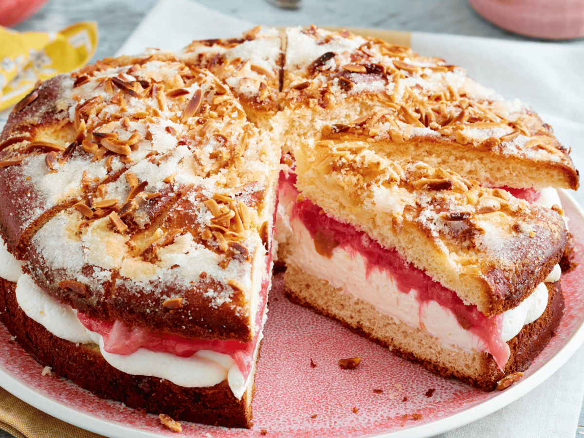 Gef&uuml;llter Butterkuchen mit Sahne und Rhabarber auf rosanem Teller.