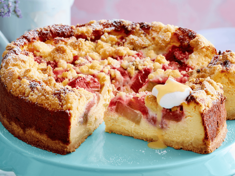 Rhabarber-Käsekuchen auf einer grünen Tortenplatte.