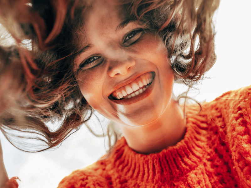 Junge Frau schaut lächelnd von oben in Kamera.