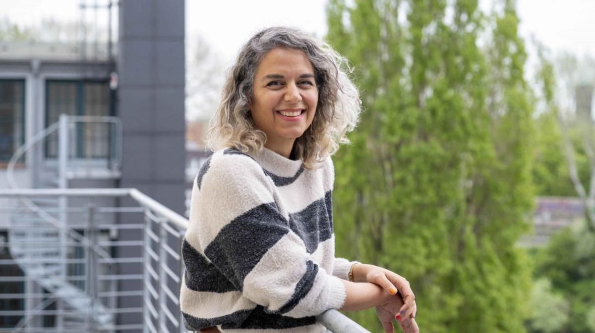 Donya Golafshan lehnt lässig an einem Geländer.