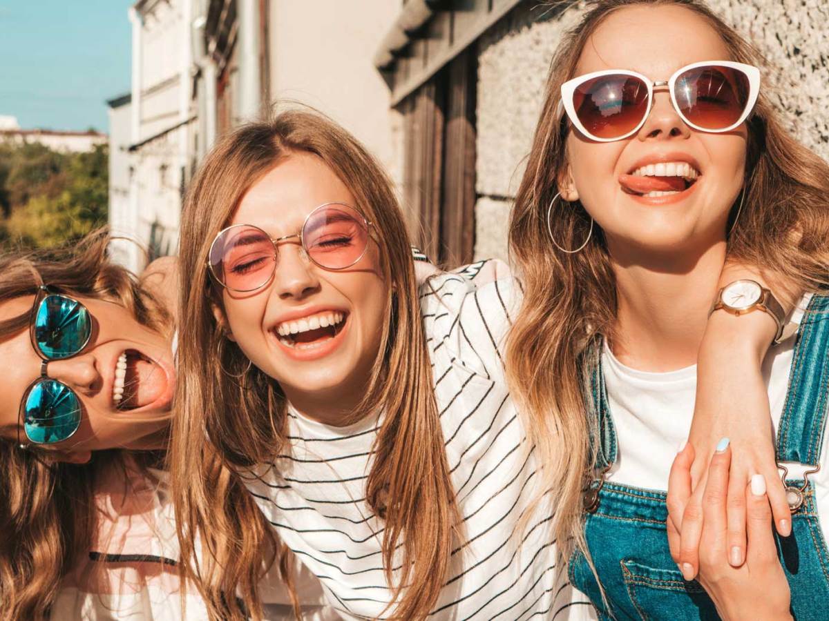 Drei Teenager-Mädchen draußen im Sonnenschein haben Spaß und albern herum.