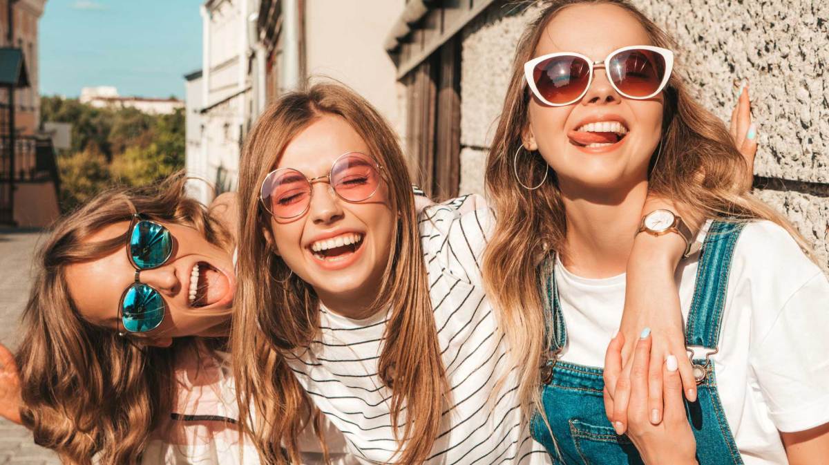 Drei Teenager-Mädchen draußen im Sonnenschein haben Spaß und albern herum.