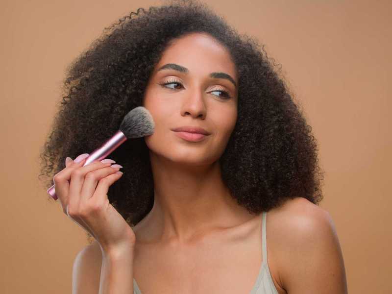 Frau trägt mit einem Pinsel Bronzer auf