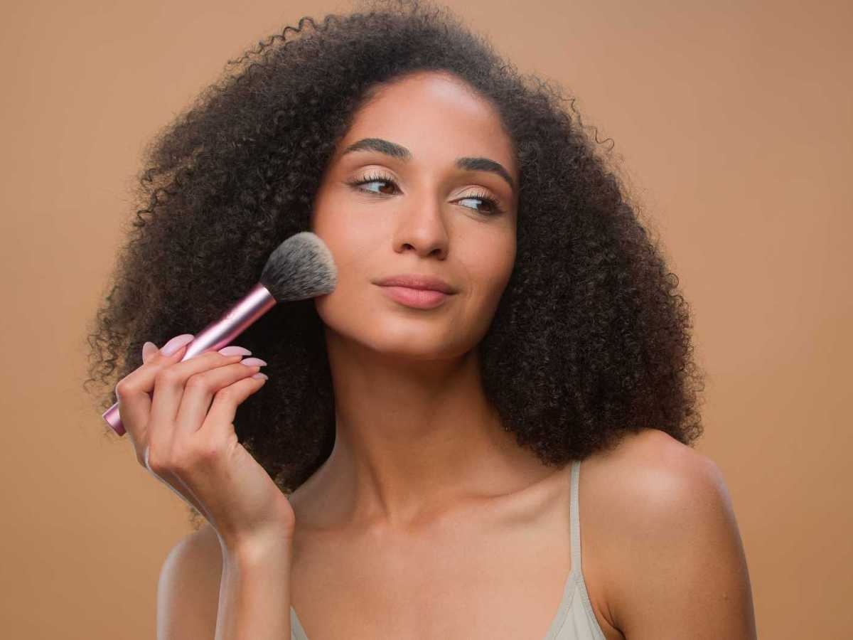Frau tr&auml;gt mit einem Pinsel Bronzer auf