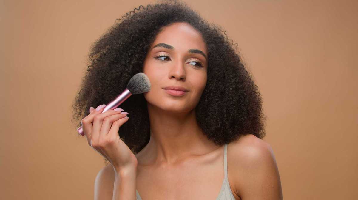 Frau trägt mit einem Pinsel Bronzer auf