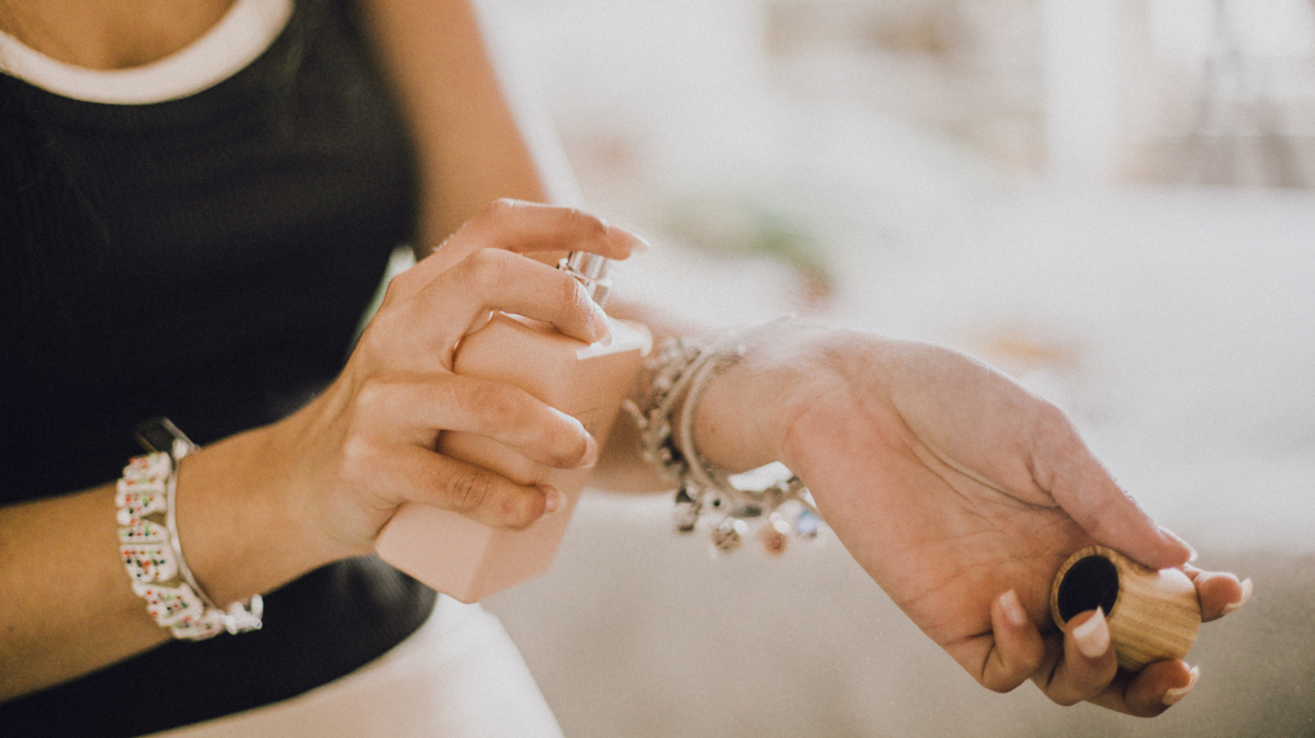 Frau, die Duft auf den Arm aufsprüht.