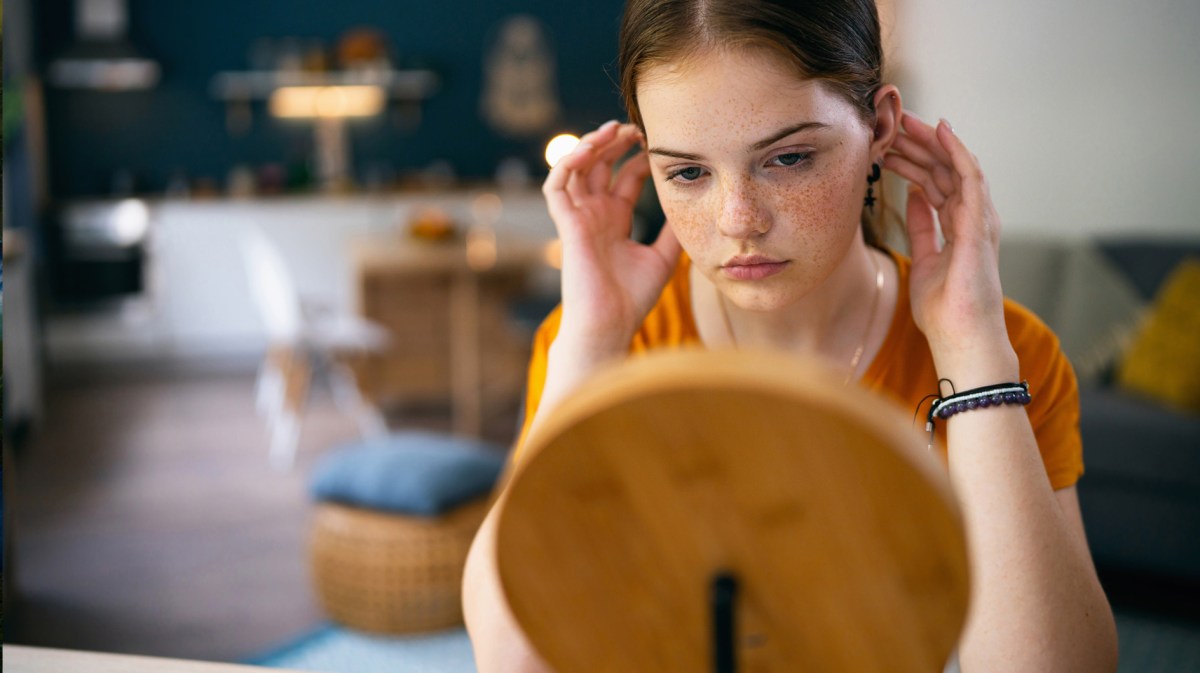 Mädchen im Teenageralter, das kritisch in den Spiegel schaut.