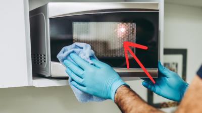 Mann macht eine Mikrowelle sauber. An der T&uuml;re sind Punkte.