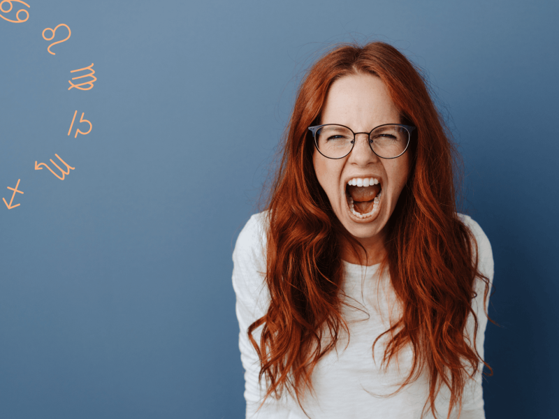 Frau mit roten Haaren und Brille „schreit“ wütend in die Kamera
