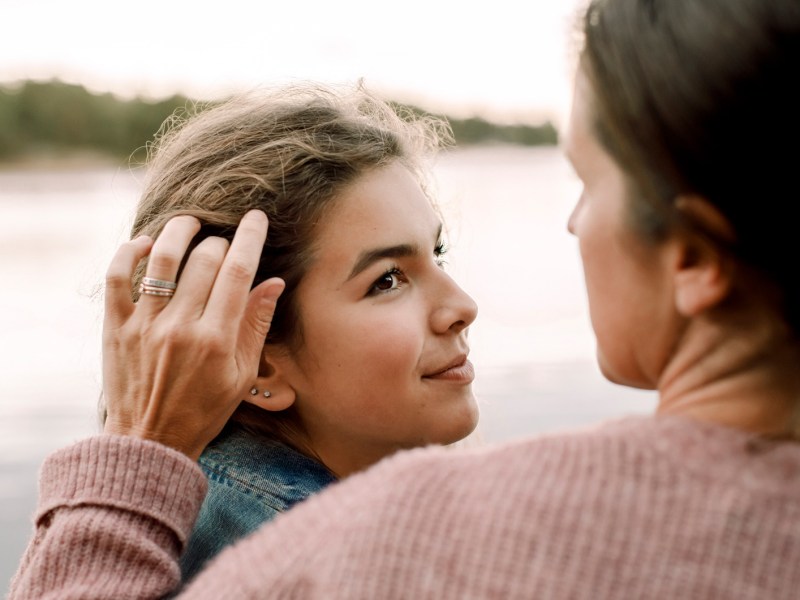 Nahaufnahme von einer Mutter, die ihrer Tochter Haare hinter das Ohr streicht.