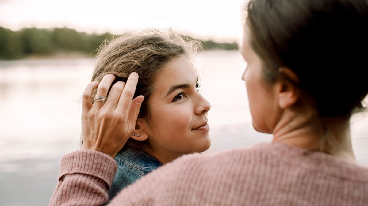 Nahaufnahme von einer Mutter, die ihrer Tochter Haare hinter das Ohr streicht.
