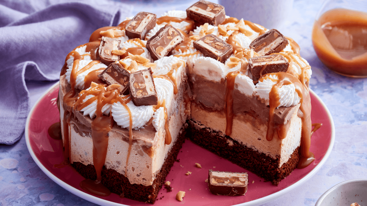 Eistorte mit Karamell und Erdnussriegeln auf einem roten Teller.