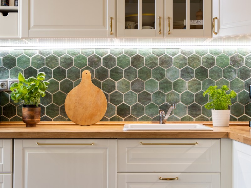 Gepflegte weiße Küche mit grünen Fließen