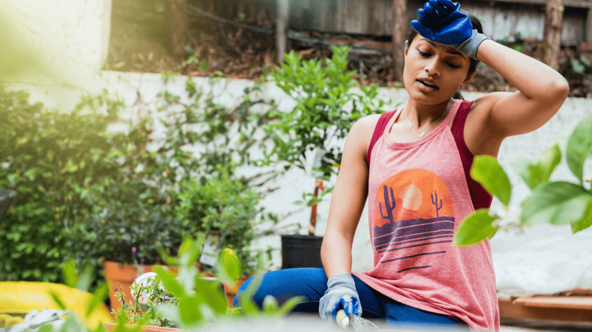 Frau schwitzt bei Gartenarbeit.
