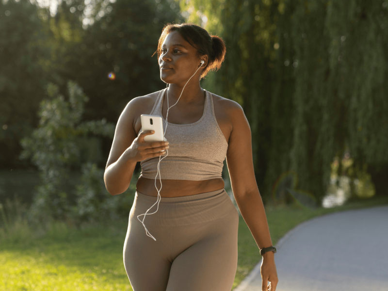 Junge, Schwarze Frau spaziert in Sportkleidung draußen.