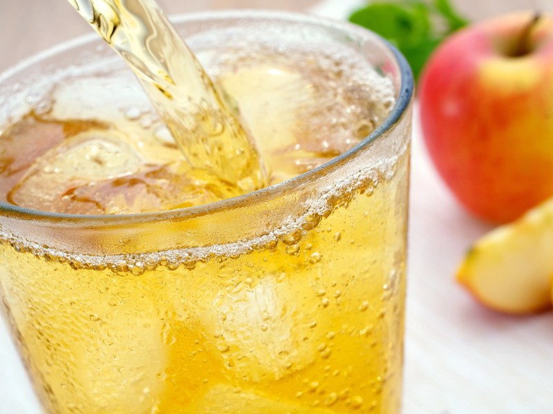 Apfelsaftschorle wir din ein Glas mit Eiswürfeln gegossen