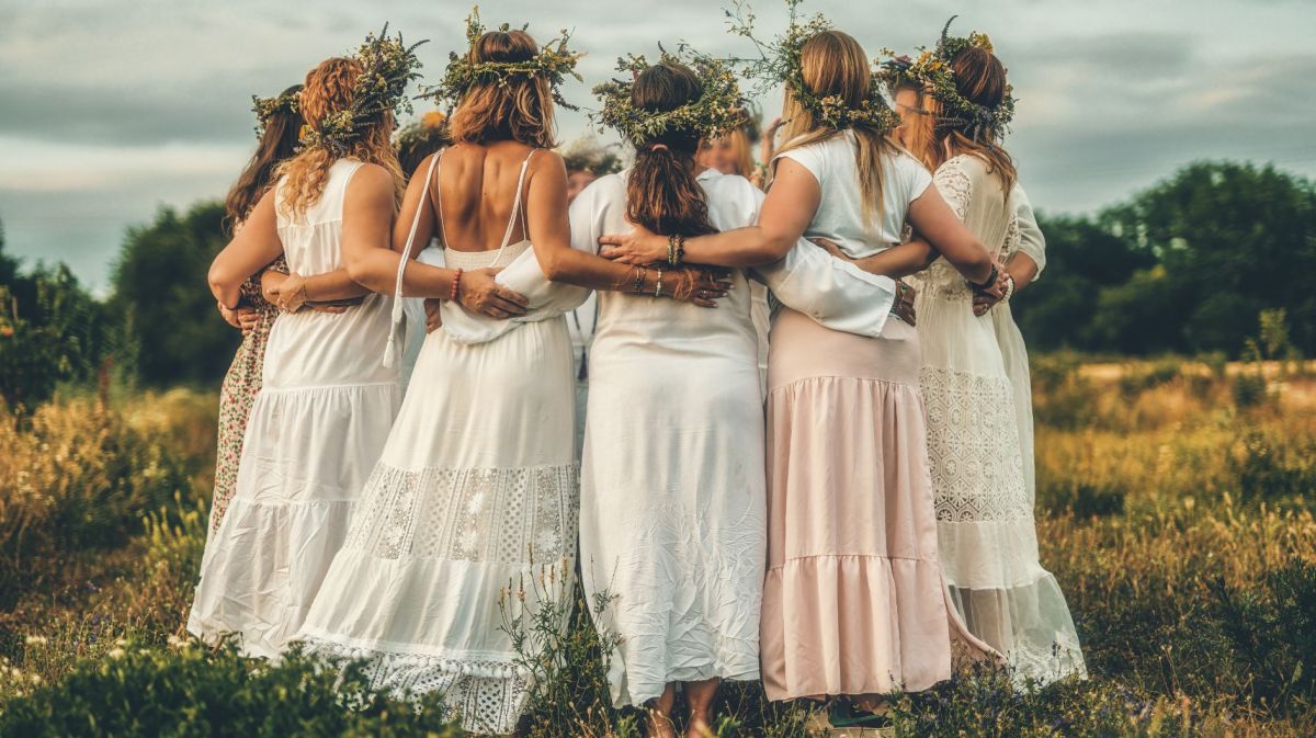 Frauen tanzen in weißen Kleidern und mit Blumenkränzen im Haar